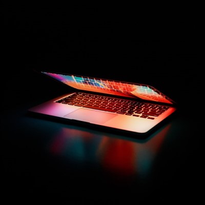 A turned on, half-open laptop in the dark. Photo by Junior Teixeira from Pexels.